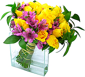 Magníficas rosas de intenso amarelo em contraste com a colorida alstroeméria importada em moderna base de vidro.